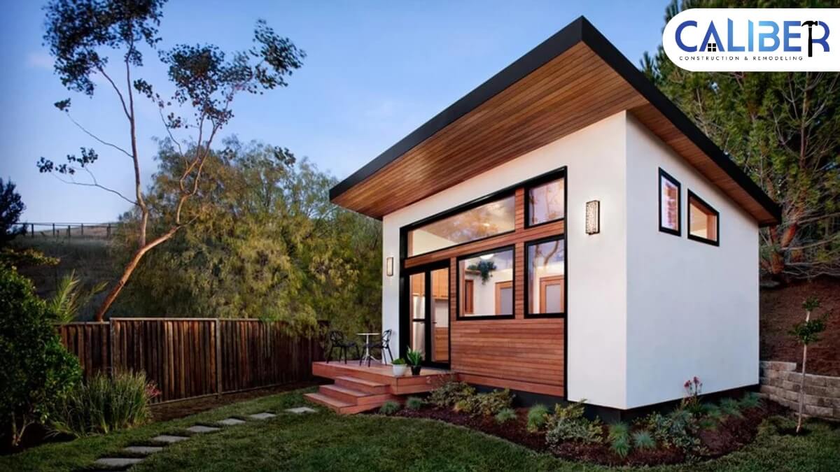 adu-sideview-featured A small house featuring a wooden deck and a wooden fence, surrounded by greenery, showcasing a cozy outdoor living space.